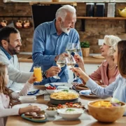 Foto de uma família: avós, pais e netos fazendo um brinde num almoço