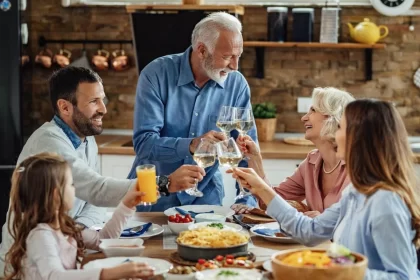 Foto de uma família: avós, pais e netos fazendo um brinde num almoço