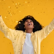 Mulher negra com os braços para o alto comemorando o novo ano. O orixá do ano é o Xapanã, o senhor das guerras