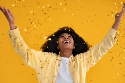 Mulher negra com os braços para o alto comemorando o novo ano. O orixá do ano é o Xapanã, o senhor das guerras