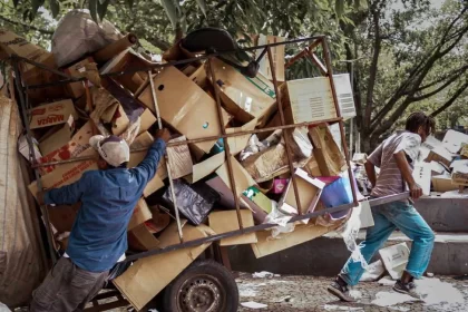 Dois catadores com uma carrocinha carregada de papelão. Autor fala sobre o trabalho humano