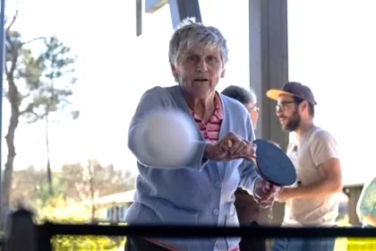 Mulher idosa joga ping pong na Vila Alzheimer