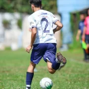 Jogador carregando a bola no pé no gramado. Projetos sociais