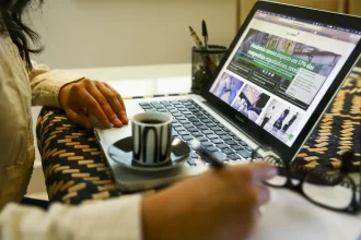 Mulher com um lap top à frente. No teletrabalho, o local de trabalho é em casa