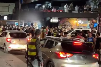 Cena do carnaval em Porto Alegre, pessoas nas ruas sob os olhares de policiais