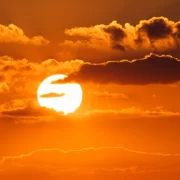 Foto do sol com o céu alaranjado, ondas de calor