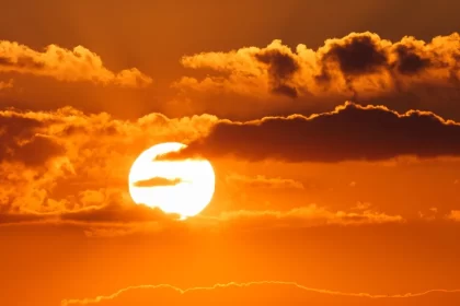 Foto do sol com o céu alaranjado, ondas de calor