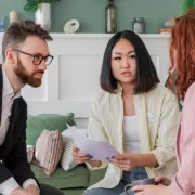 Casal examina um papel e fala com advogada. Regime de bens.