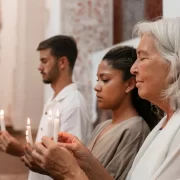 Pessoas dentro de uma igreja segurando velas acesas, Autor fala em fé.