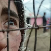 Homem olha por trás das grades de um presídio