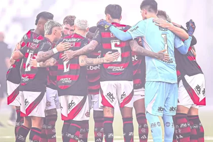 Jogadores do flamengo se abraçam no centro do campo. O time é o maior representante dos rubro-negros do país.