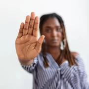 Mulher jovem, negra, com a palma estendida para frente, chega de racismo