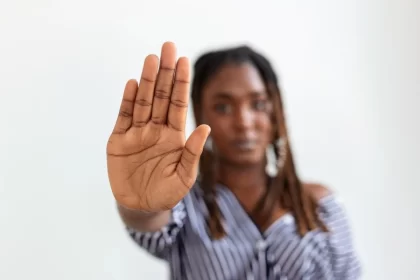 Mulher jovem, negra, com a palma estendida para frente, chega de racismo