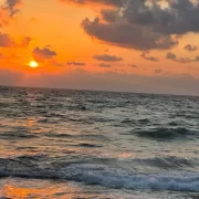 Um céu laranja do por do sol, o sol se encontrando com o mar