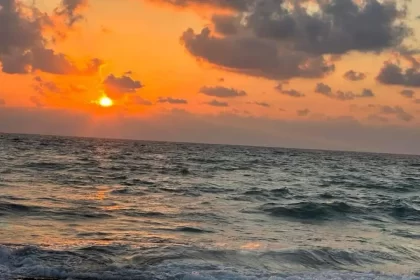 Um céu laranja do por do sol, o sol se encontrando com o mar