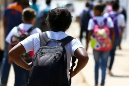 Foto de crianças de costas saindo da escola. Autora fala em abuso e violência contra crianças.