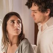 Um casal se olha seriamente, autora fala das histórias que se repetem.