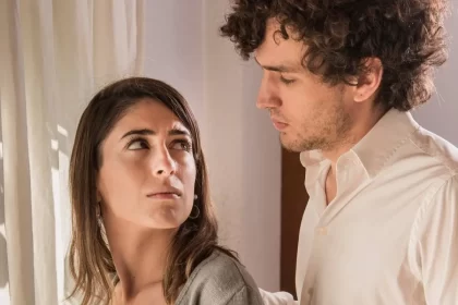 Um casal se olha seriamente, autora fala das histórias que se repetem.